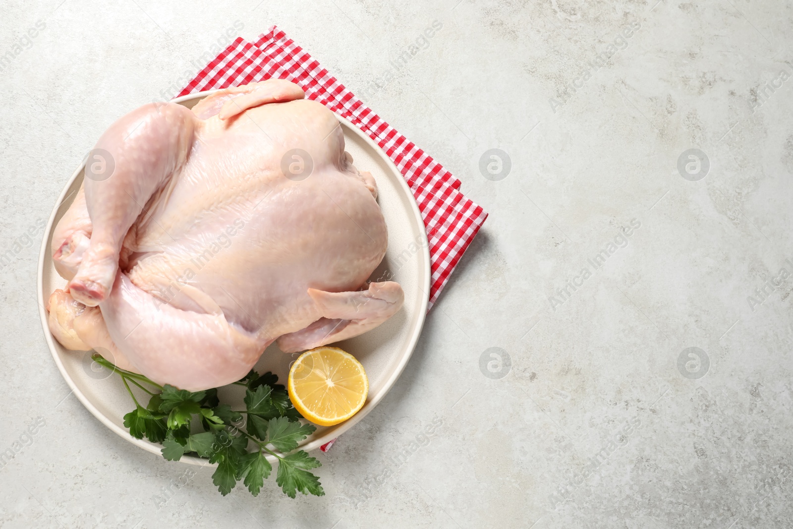 Photo of Fresh raw chicken with lemon and parsley on light grey table, top view. Space for text