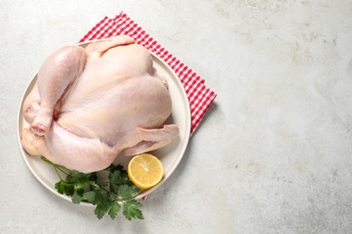 Fresh raw chicken with lemon and parsley on light grey table, top view. Space for text