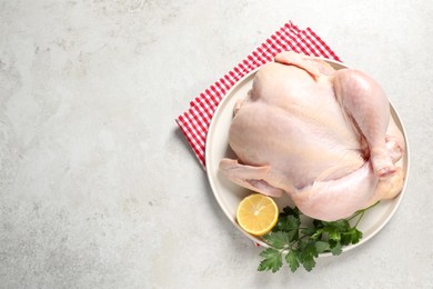 Photo of Fresh raw chicken with lemon and parsley on light grey table, top view. Space for text