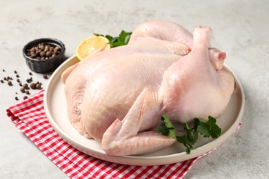 Photo of Fresh raw chicken with spices and lemon on light grey table