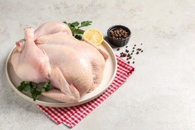 Photo of Fresh raw chicken with spices and lemon on light grey table