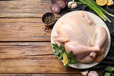 Photo of Fresh raw chicken with different products on wooden table, flat lay. Space for text