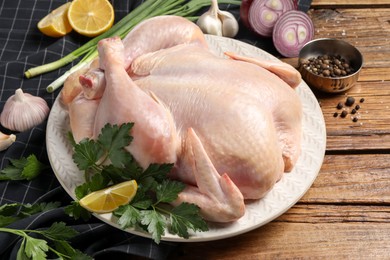 Photo of Fresh raw chicken with different products on wooden table