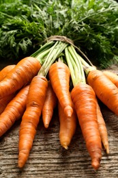 Photo of Bunch of tasty ripe juicy carrots on wooden table, closeup