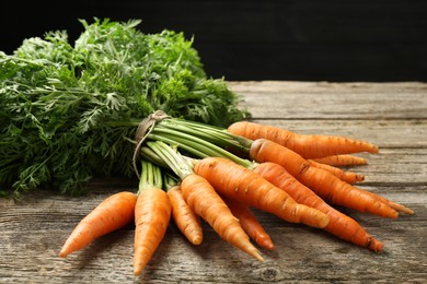 Photo of Bunch of tasty ripe juicy carrots on wooden table