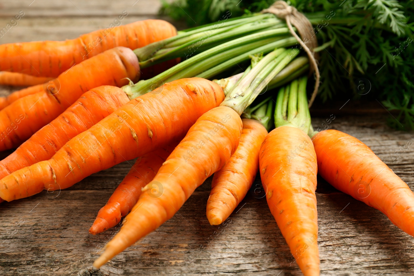 Photo of Bunch of tasty ripe juicy carrots on wooden table, closeup