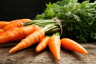 Tasty ripe juicy carrots on wooden table, closeup