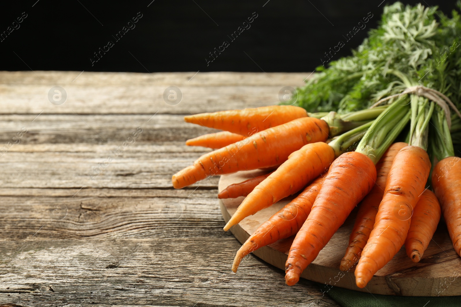 Photo of Tasty ripe juicy carrots on wooden table, space for text