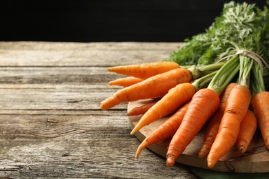 Photo of Tasty ripe juicy carrots on wooden table, space for text