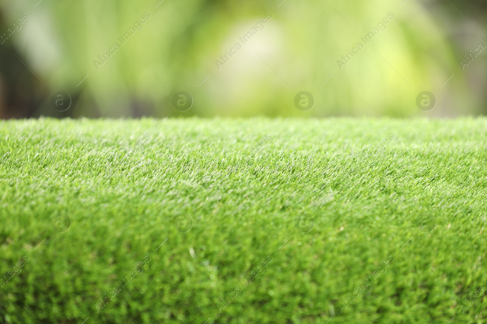 Photo of Green artificial grass against blurred background, closeup