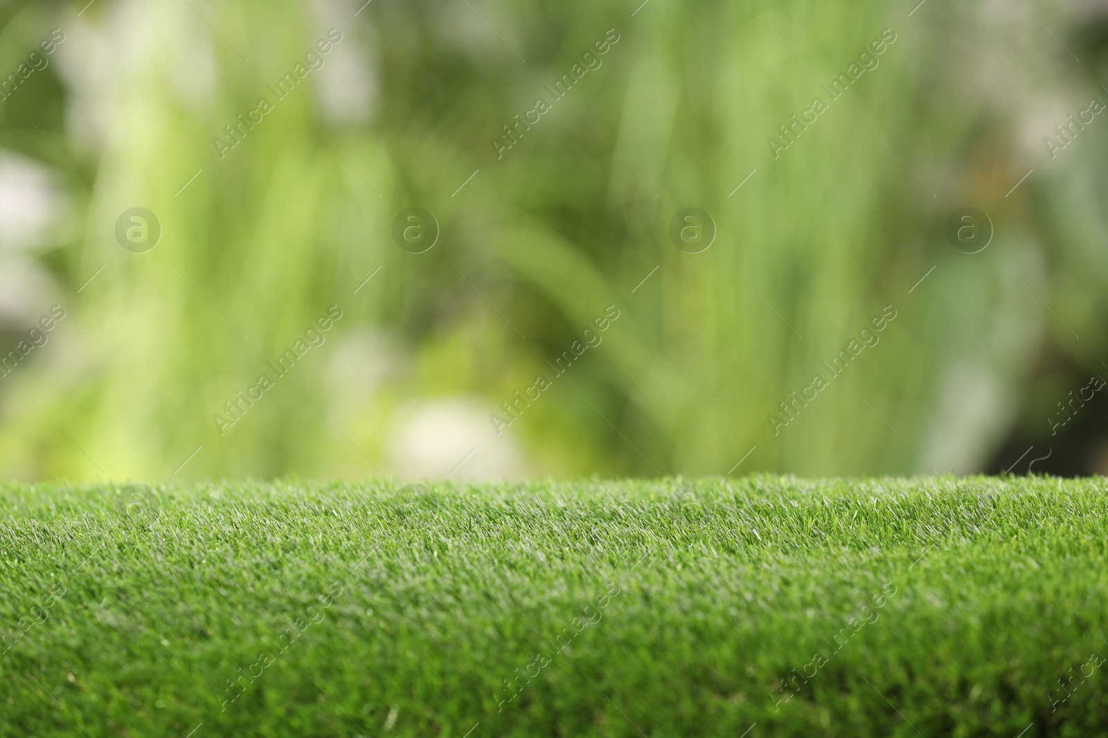 Photo of Green artificial grass against blurred background, closeup