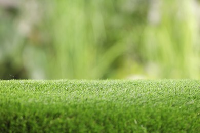 Photo of Green artificial grass against blurred background, closeup