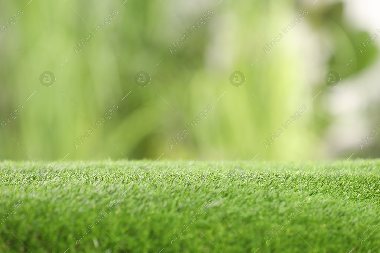 Photo of Green artificial grass against blurred background, closeup