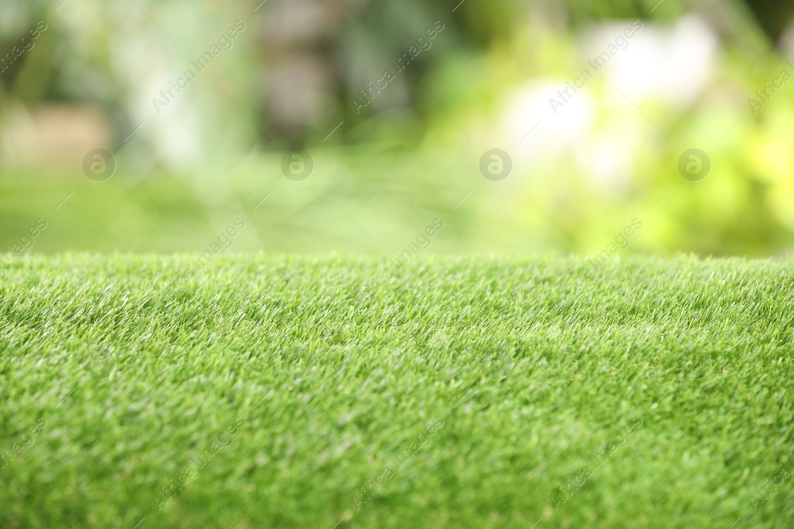 Photo of Green artificial grass against blurred background, closeup