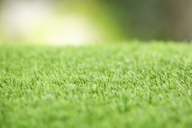 Photo of Green artificial grass against blurred background, closeup