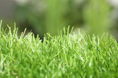 Green artificial grass against blurred background, closeup