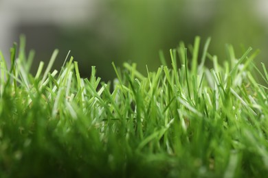 Photo of Green artificial grass against blurred background, closeup