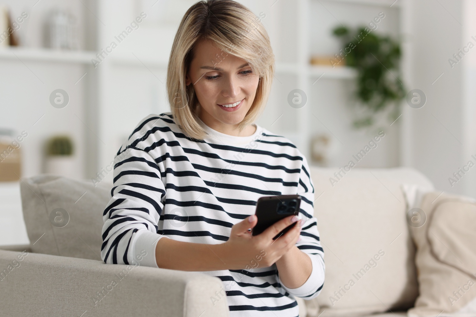 Photo of Happy woman using mobile phone at home