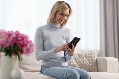 Happy woman using mobile phone at home