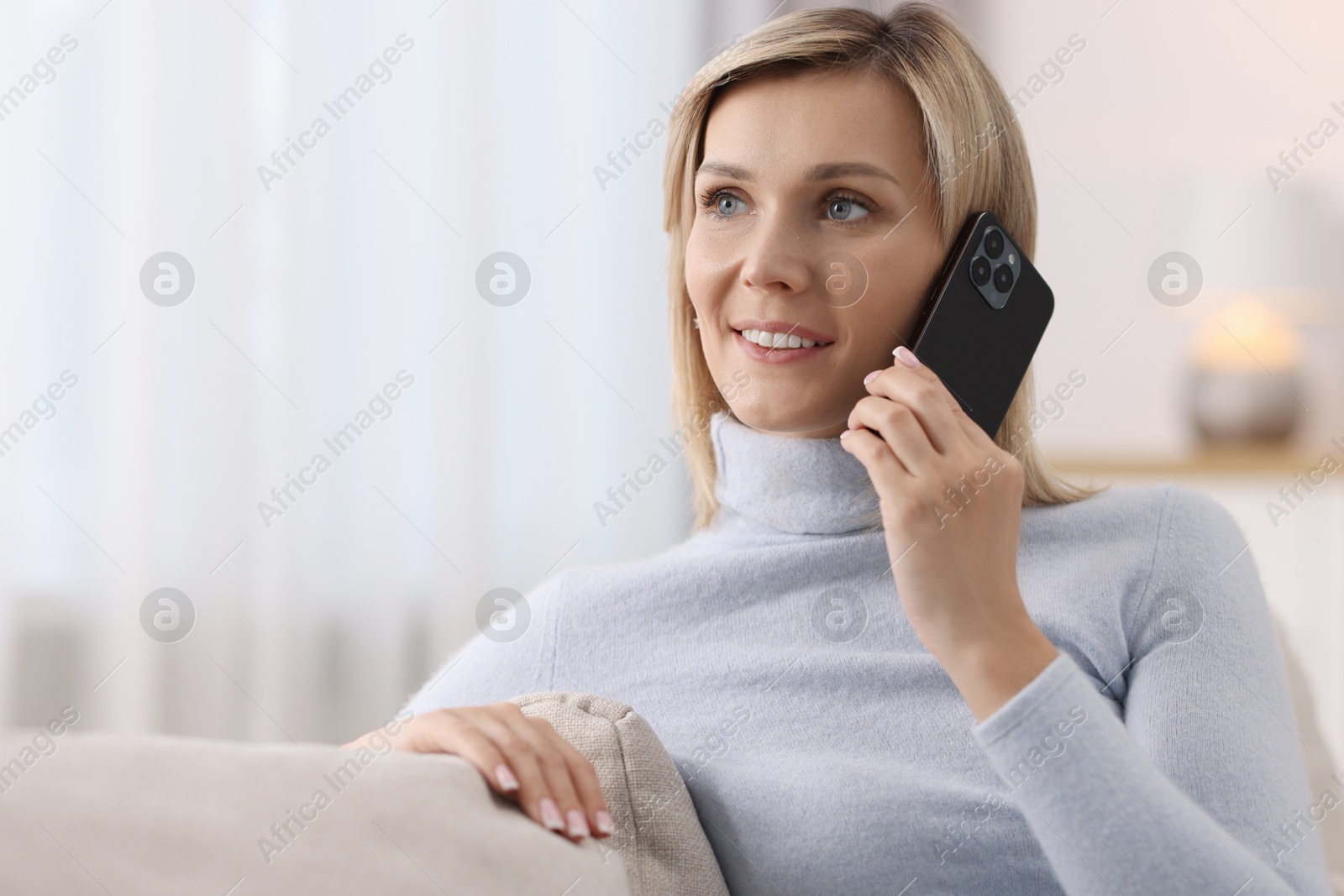 Photo of Happy woman talking on phone at home, space for text