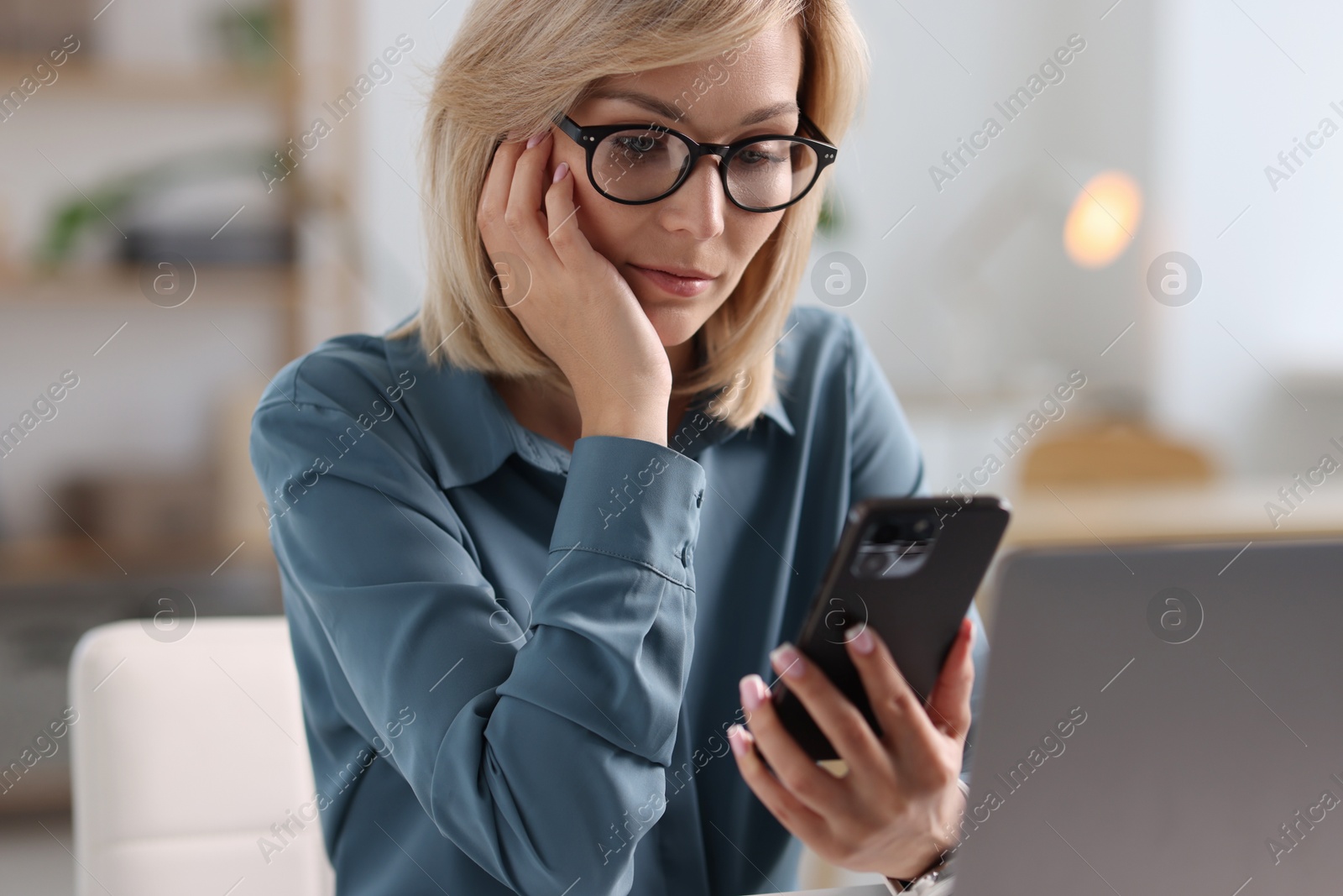 Photo of Woman using mobile phone at table indoors