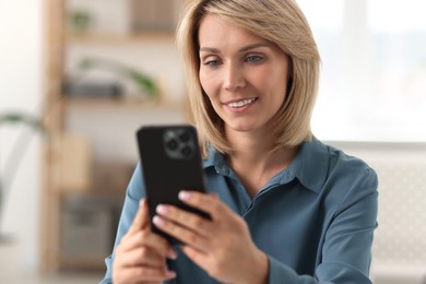 Happy woman using mobile phone at home