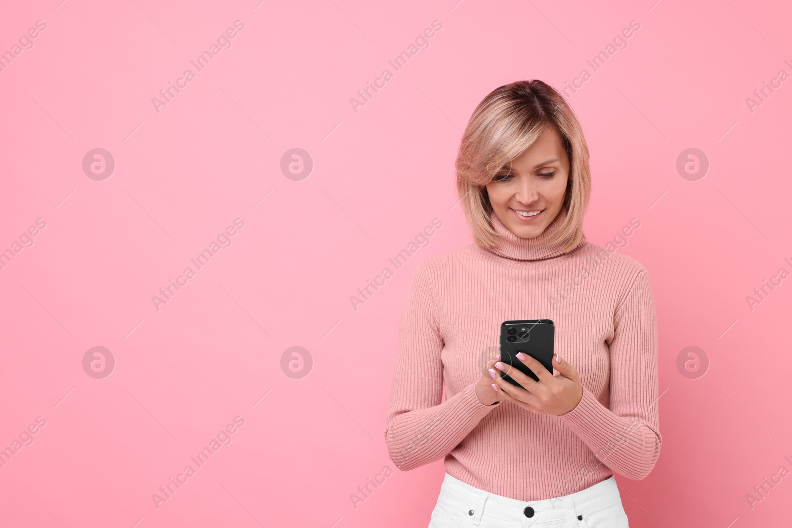 Photo of Happy woman with phone on pink background, space for text