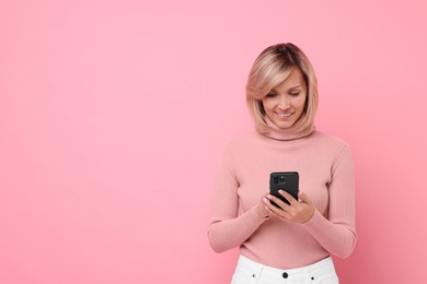 Photo of Happy woman with phone on pink background, space for text