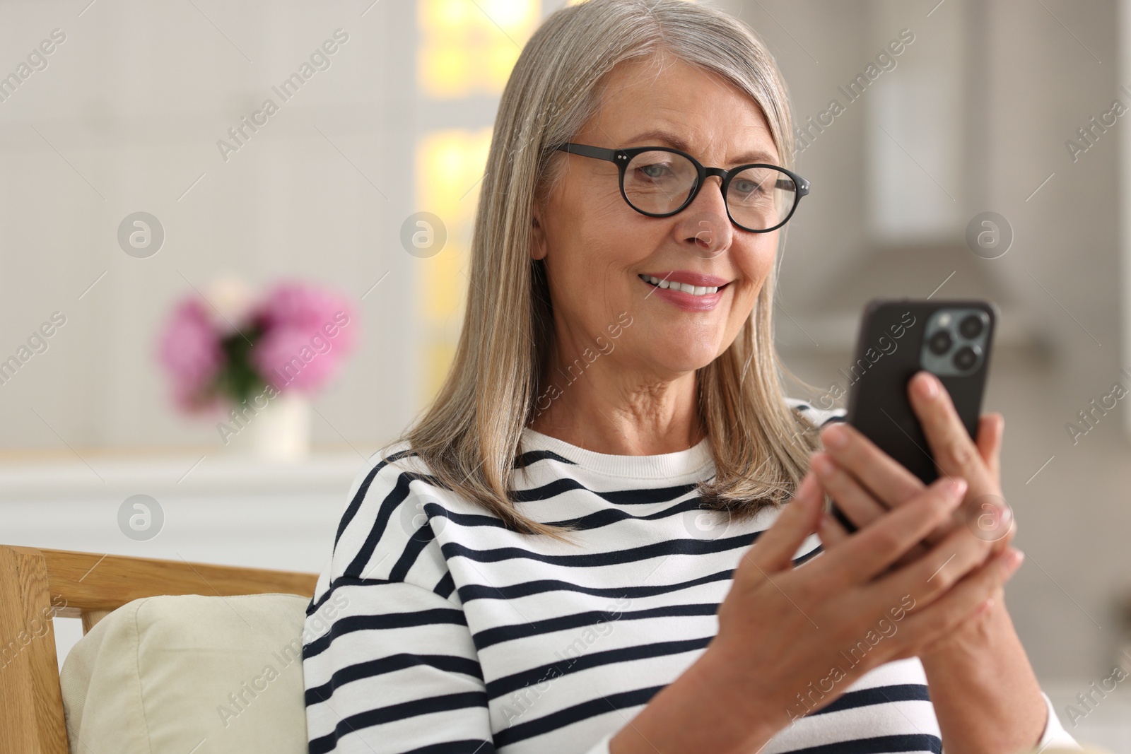 Photo of Senior woman using mobile phone at home