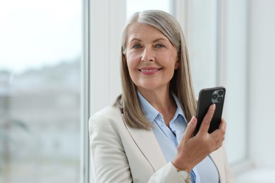 Senior woman using mobile phone at home, space for text