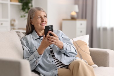 Photo of Senior woman using mobile phone at home