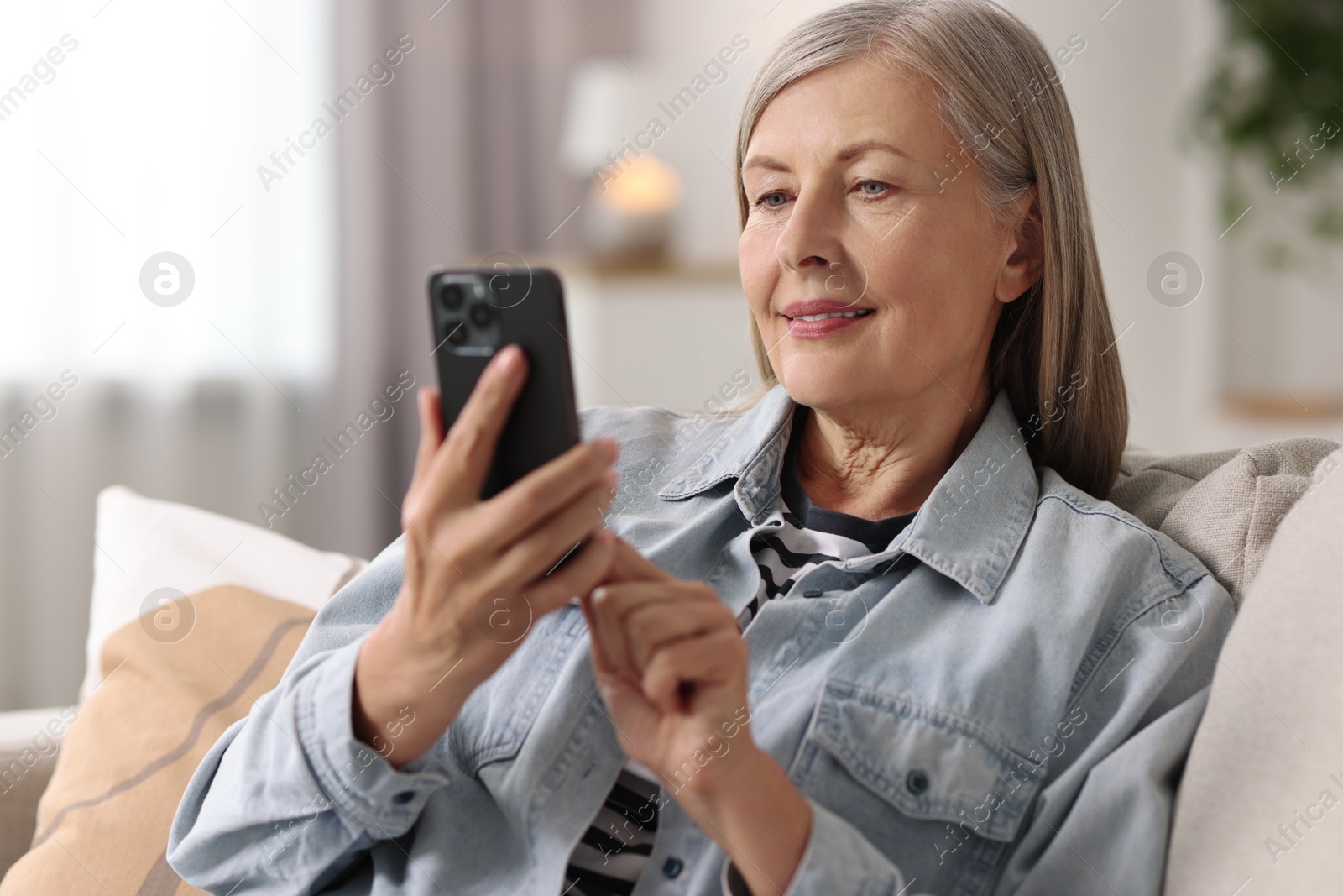 Photo of Senior woman using mobile phone at home