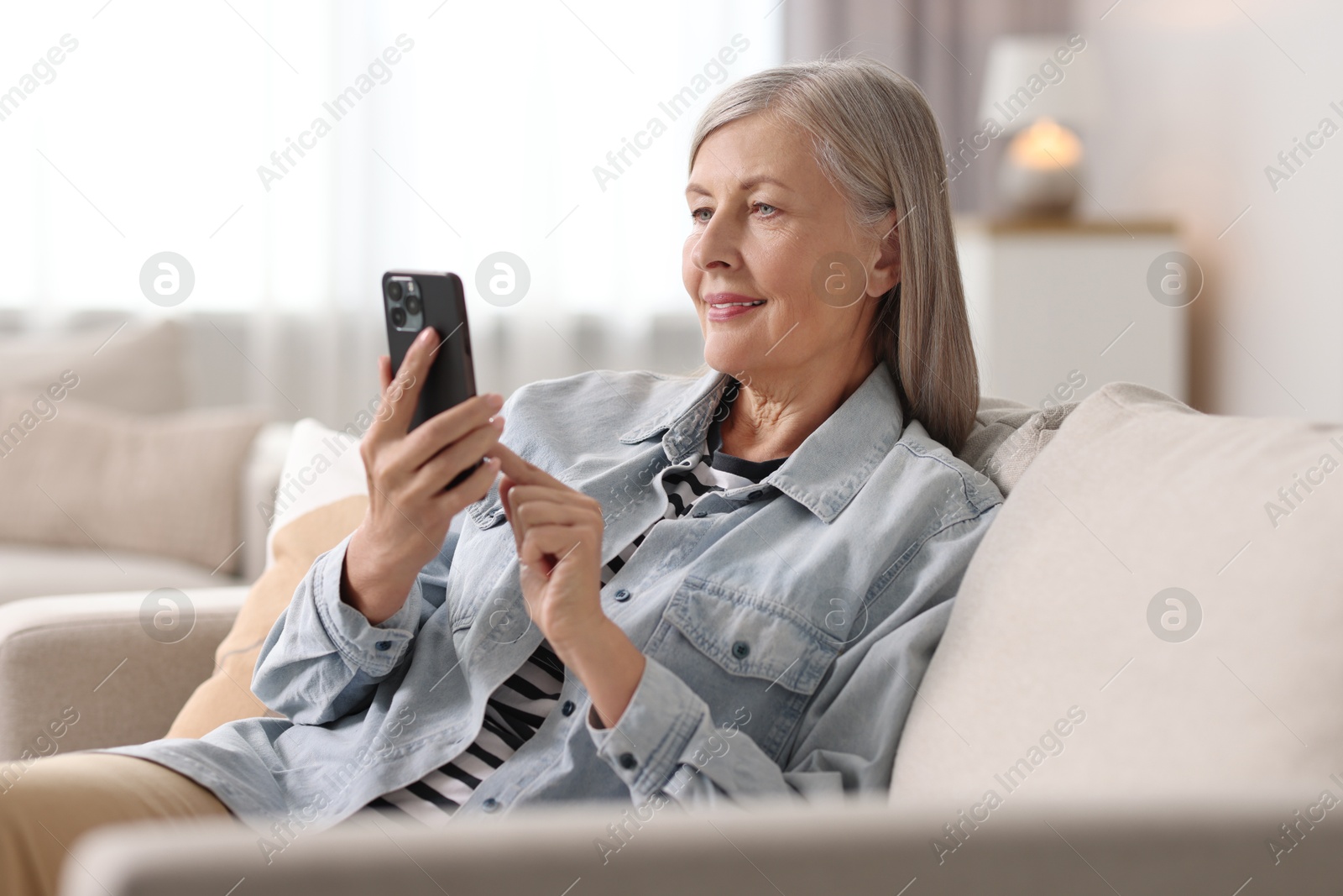 Photo of Senior woman using mobile phone at home