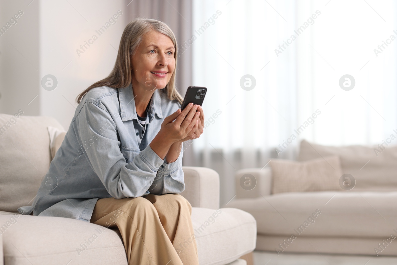 Photo of Senior woman using mobile phone at home, space for text