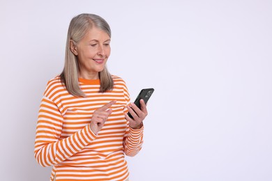 Photo of Senior woman with phone on light grey background, space for text