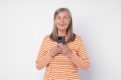 Senior woman with phone on light grey background