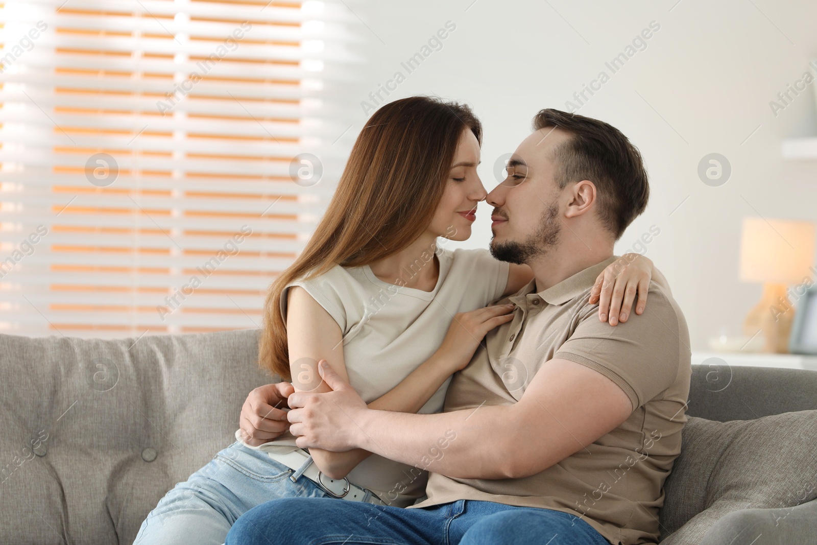 Photo of Cute couple hugging on sofa at home