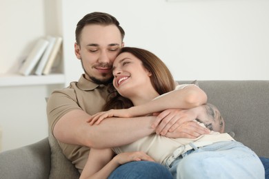 Photo of Happy couple hugging on sofa at home