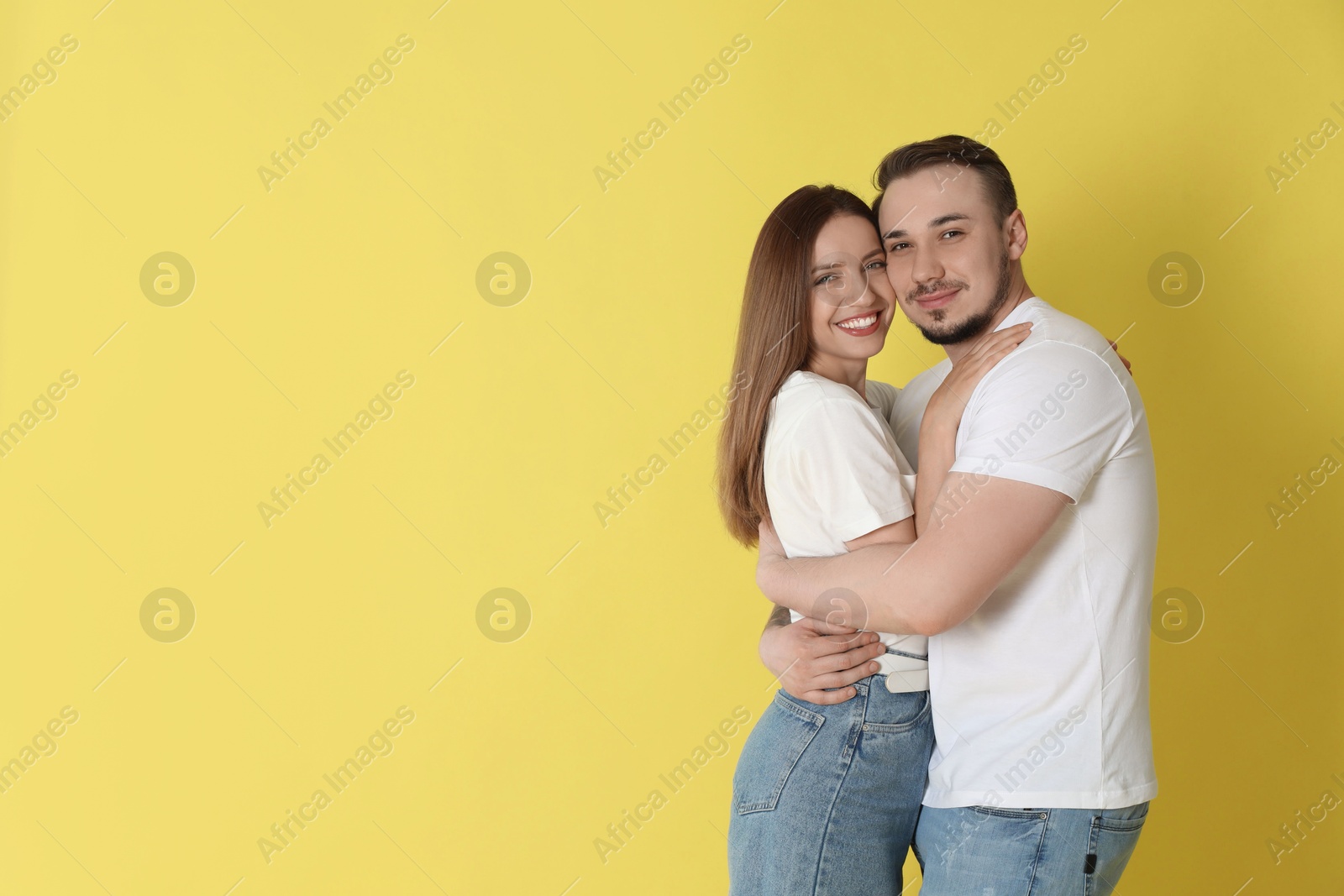 Photo of Happy couple hugging on yellow background. Space for text
