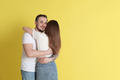 Photo of Cute couple hugging on yellow background. Space for text