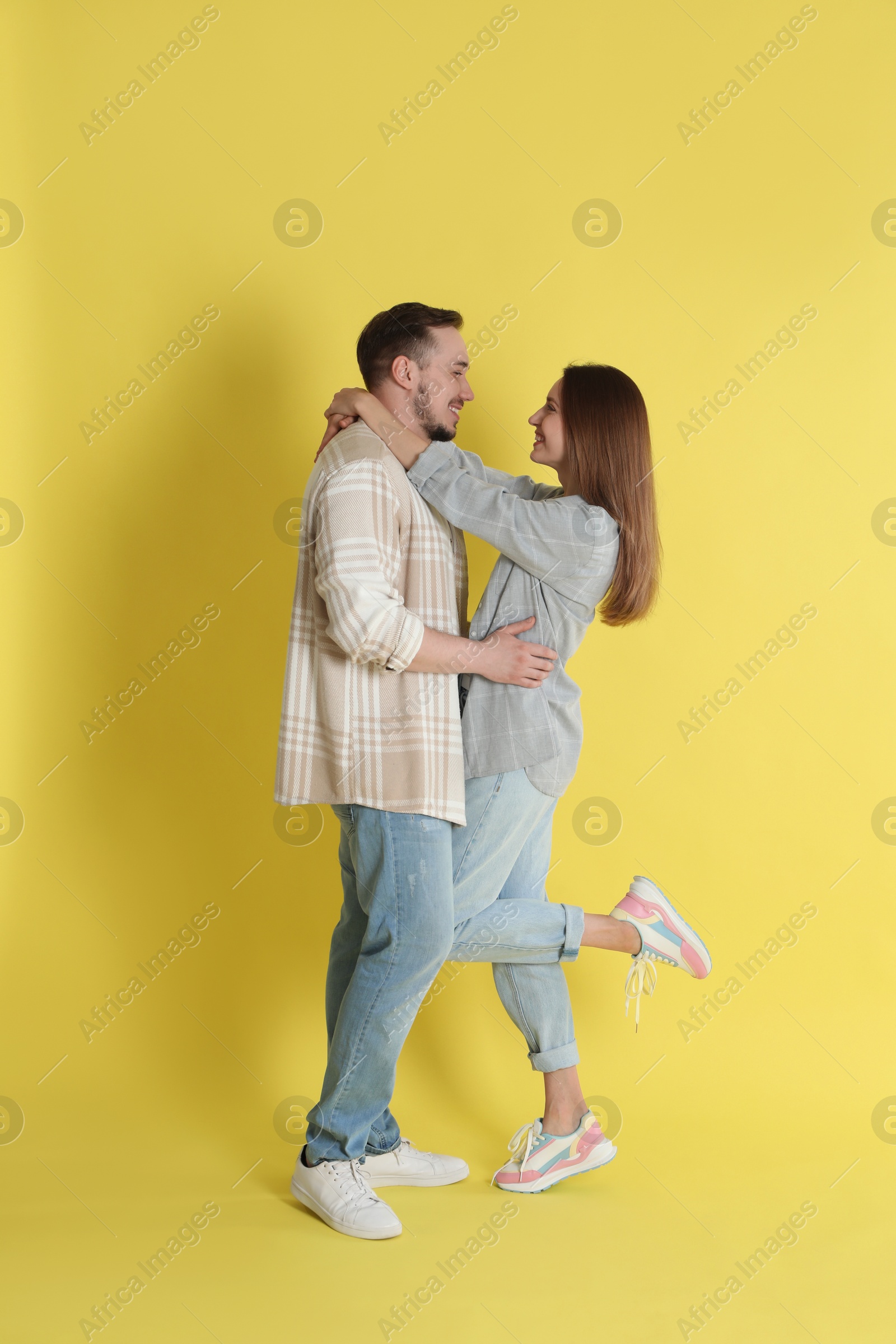 Photo of Happy couple hugging on yellow background. Strong relationship