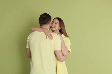 Photo of Smiling woman hugging her boyfriend on green background. Space for text