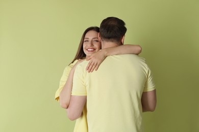 Photo of Smiling woman hugging her boyfriend on green background