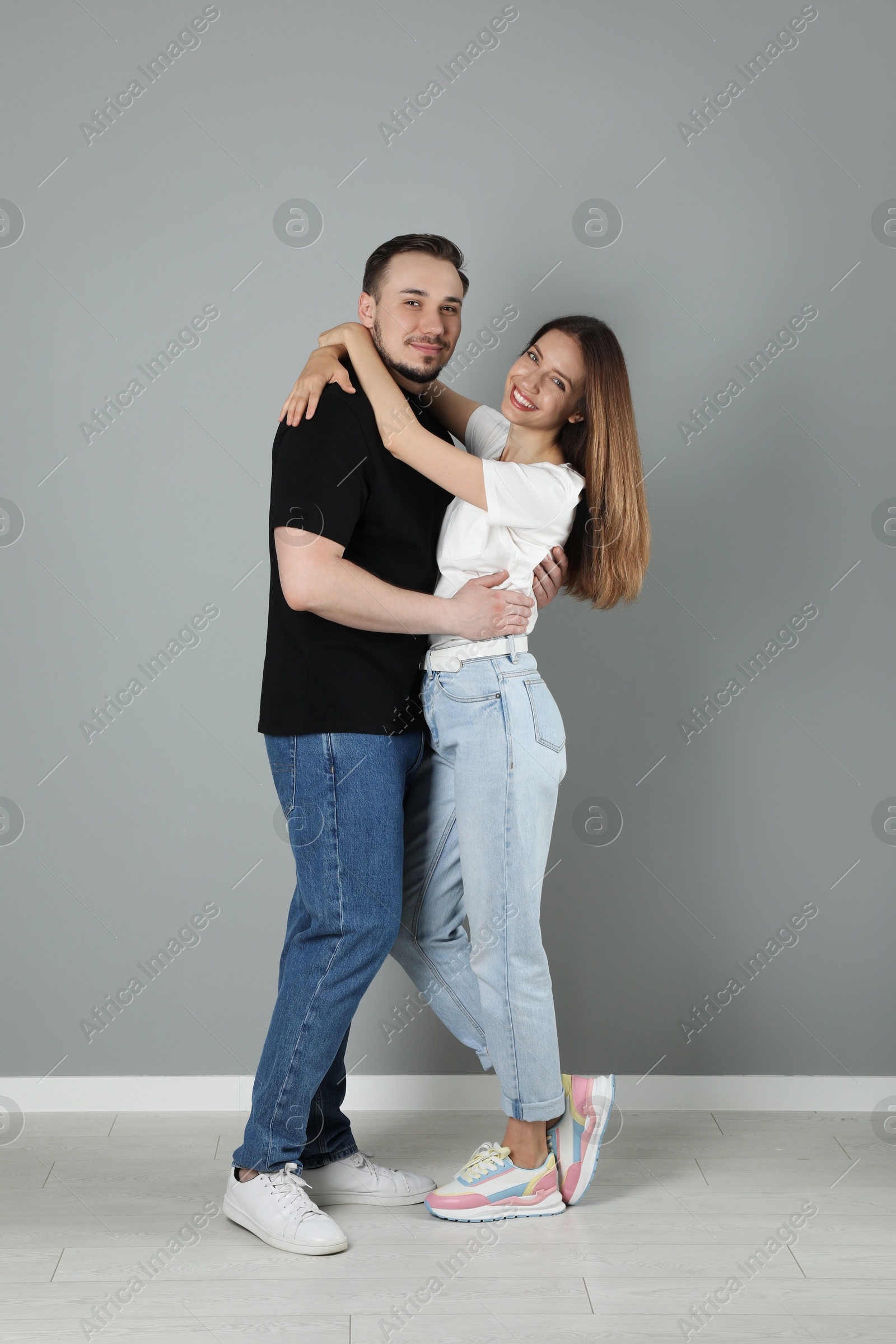 Photo of Happy couple hugging near grey wall. Strong relationship