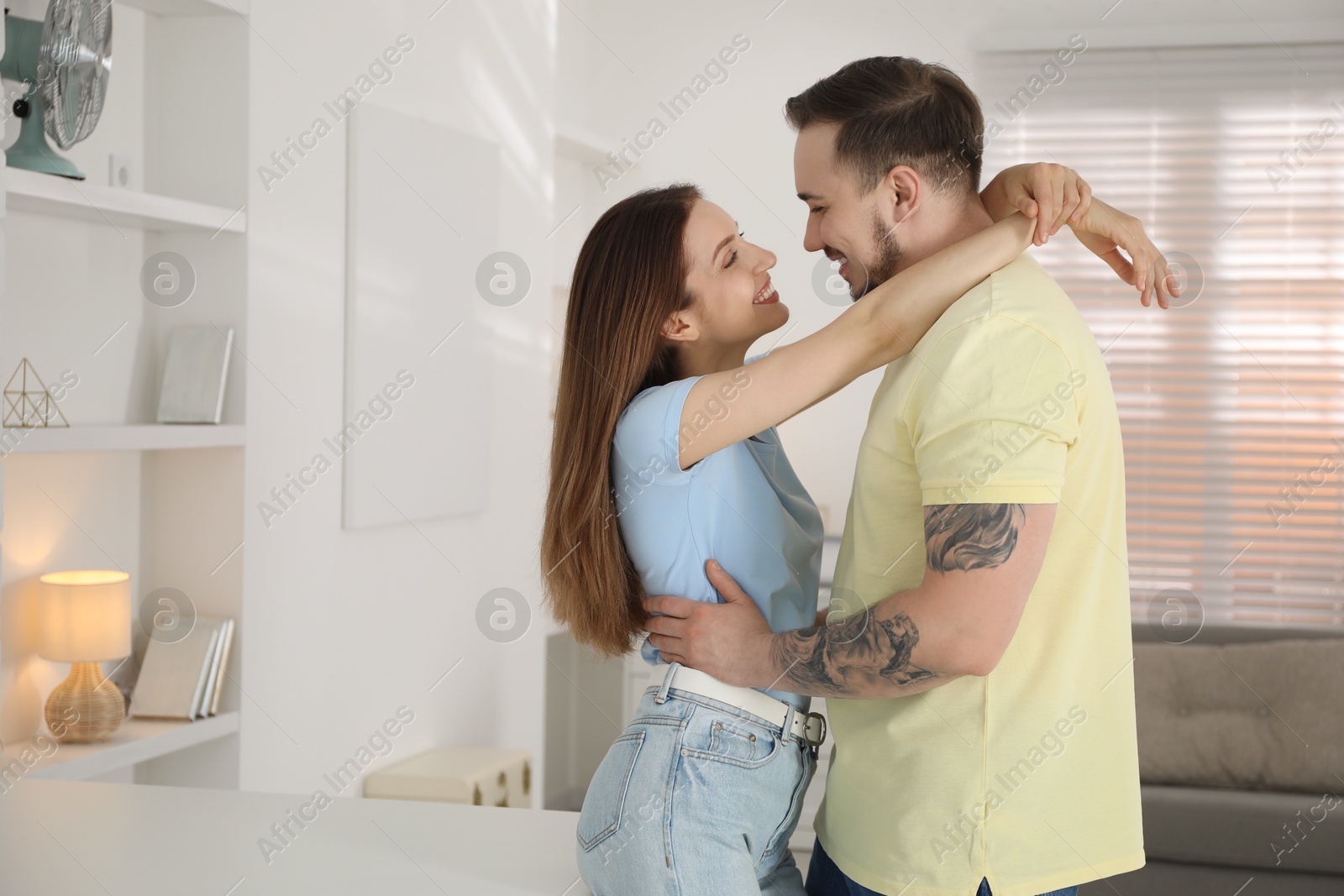 Photo of Happy couple hugging at home. Space for text