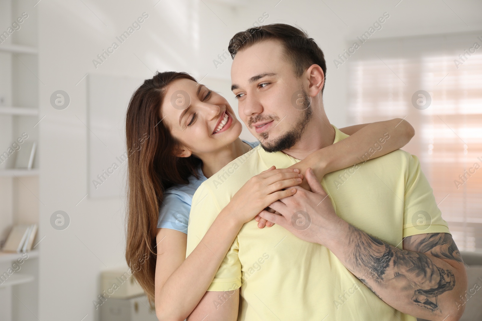 Photo of Smiling woman hugging her boyfriend at home