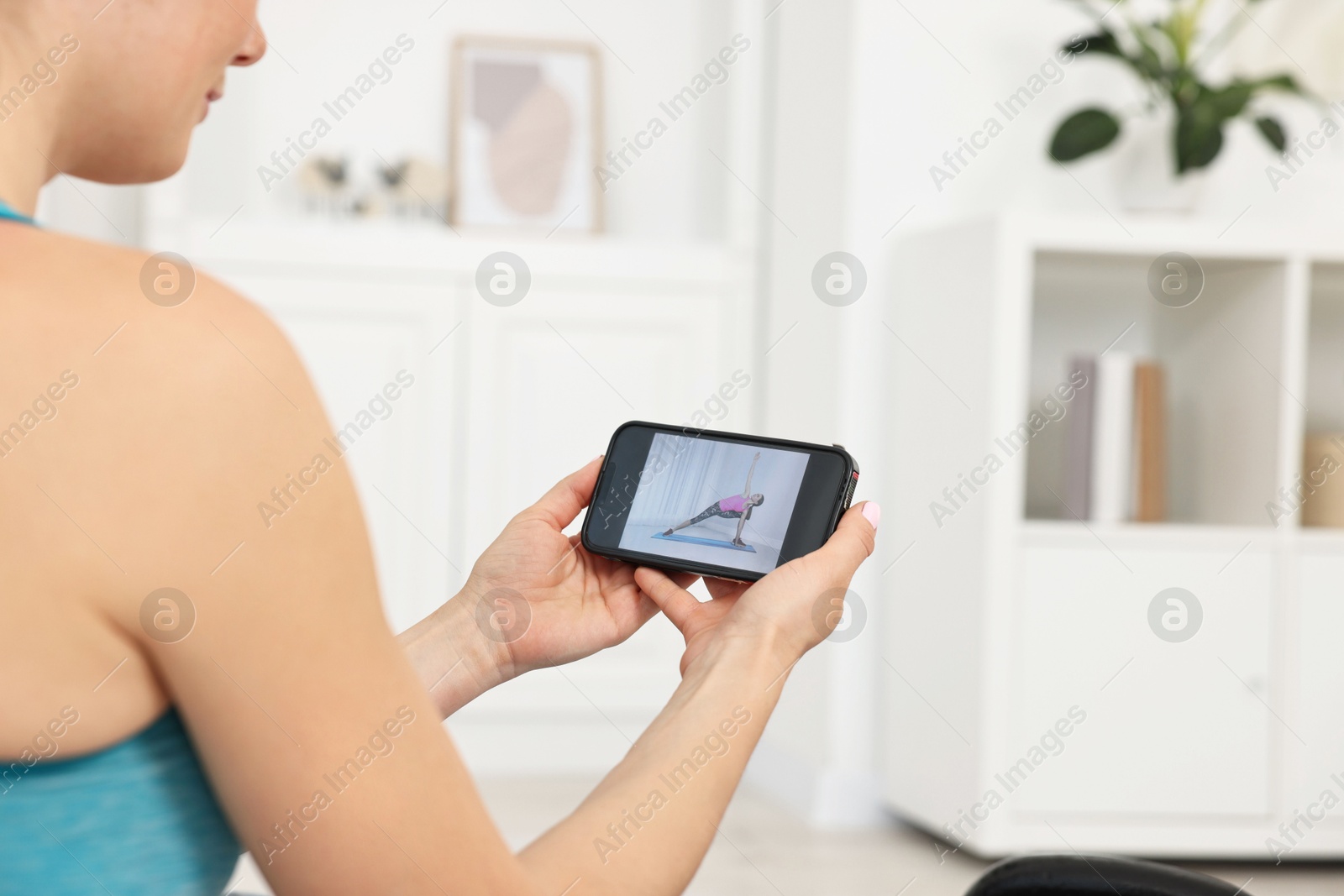 Photo of Online fitness trainer. Woman watching tutorial on smartphone at home, closeup