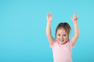 Photo of Cute little girl posing on light blue background, space for text