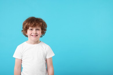 Portrait of cute little boy on light blue background, space for text