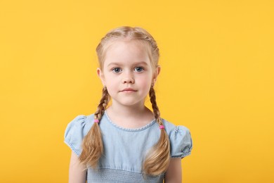 Portrait of cute little girl on orange background